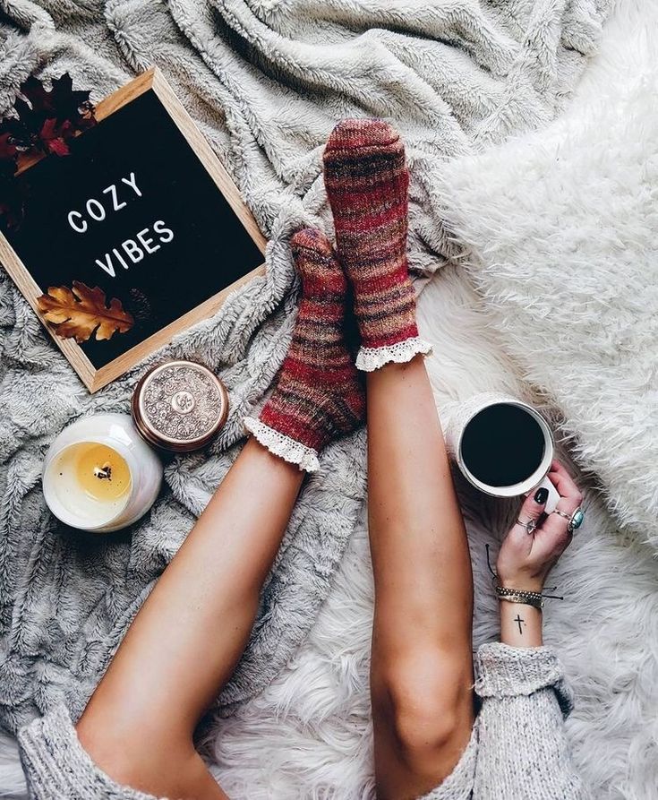 a woman laying on top of a bed next to a cup of coffee