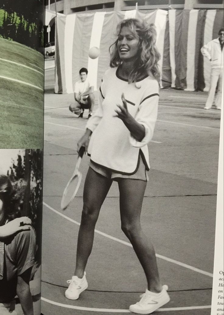 a woman holding a tennis racquet while standing on top of a tennis court