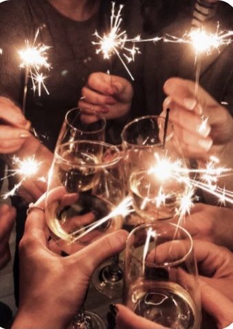 people holding wine glasses with sparklers in their hands