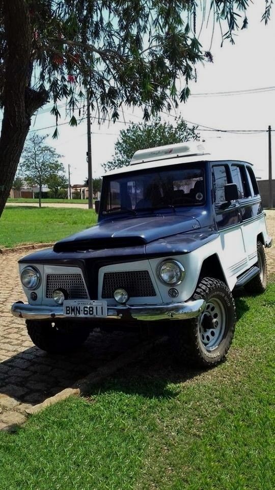 an old jeep is parked on the side of the road in front of a tree