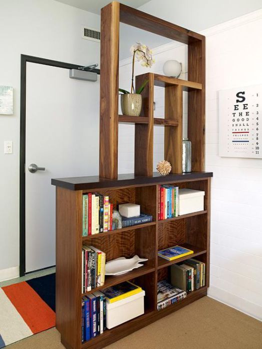 a bookshelf filled with lots of books next to a white wall in a room