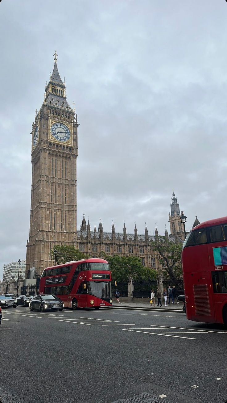 the big ben clock tower towering over the city of london as traffic passes by on a cloudy day