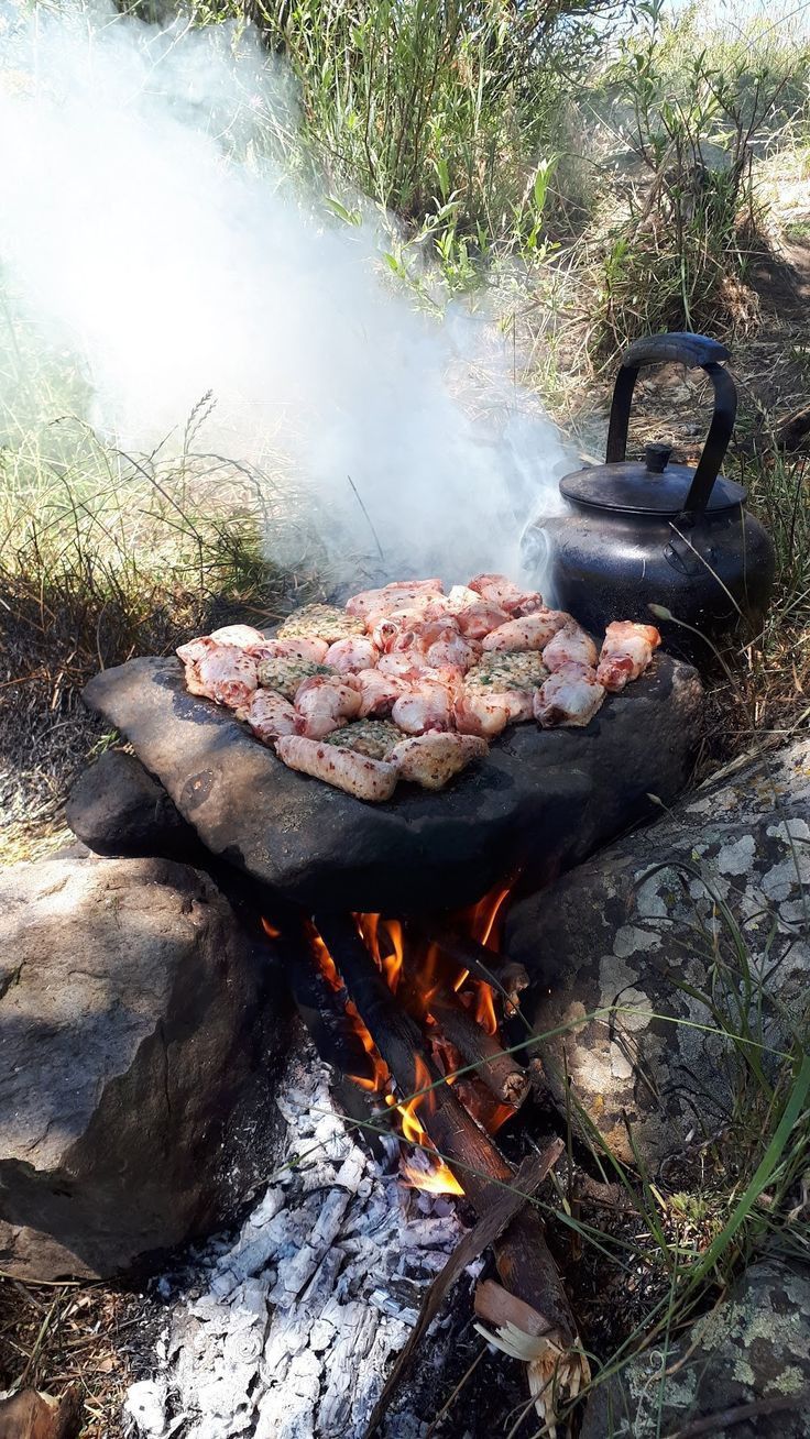 a grill that has some food on top of it in front of a fire pit