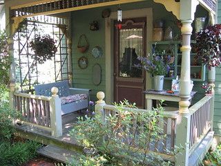 a porch with a bench and potted plants on the front steps next to it