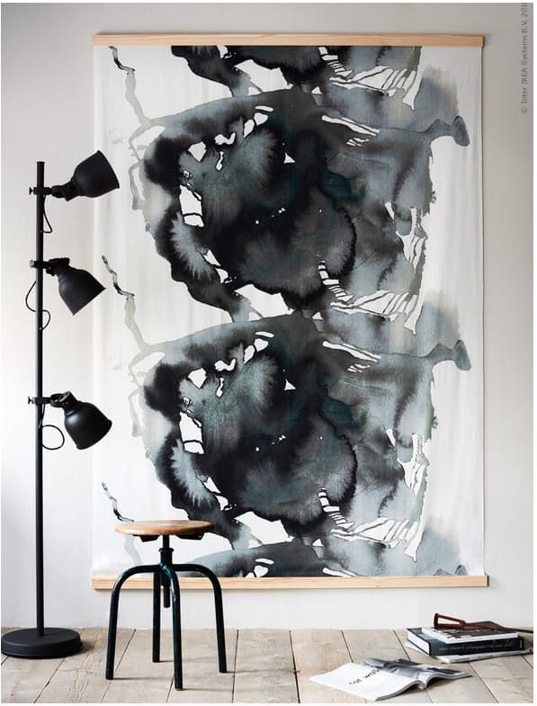 black and white painting hanging on the wall next to a table with a lamp in front of it