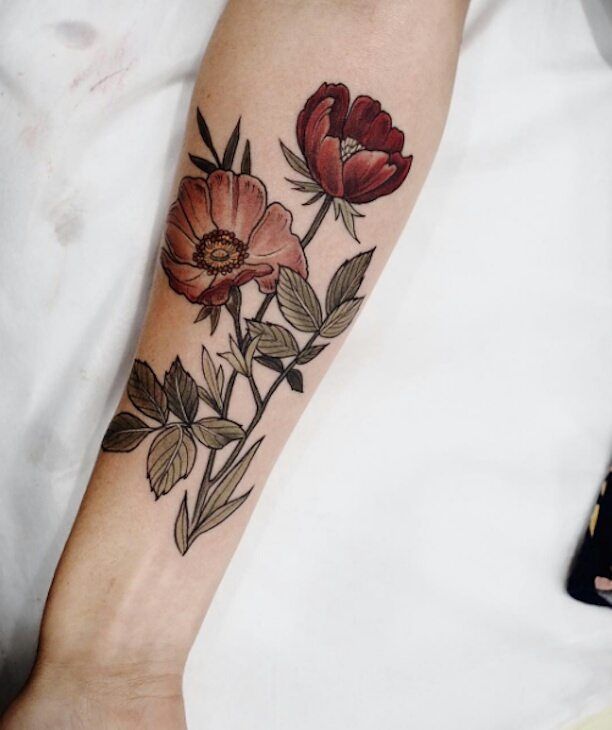 a woman's arm with flowers and leaves on the left side of her body