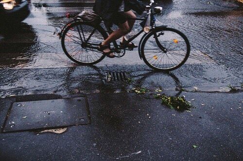 a man riding a bike down a rain soaked street