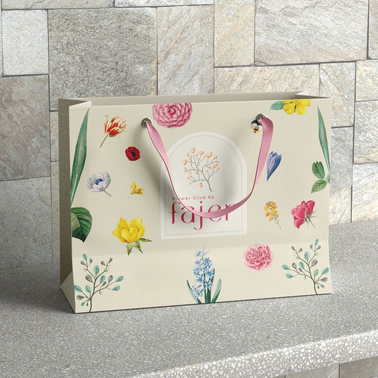 a paper bag with flowers on it sitting on top of a stone counter next to a wall