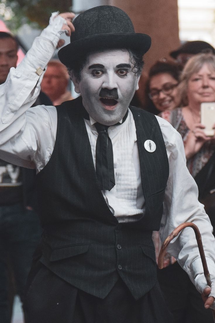 a man dressed up as the evil clown holding an umbrella and wearing a top hat