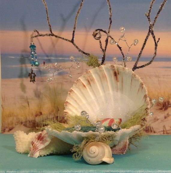 seashells are sitting on a blue table in front of an ocean scene with trees