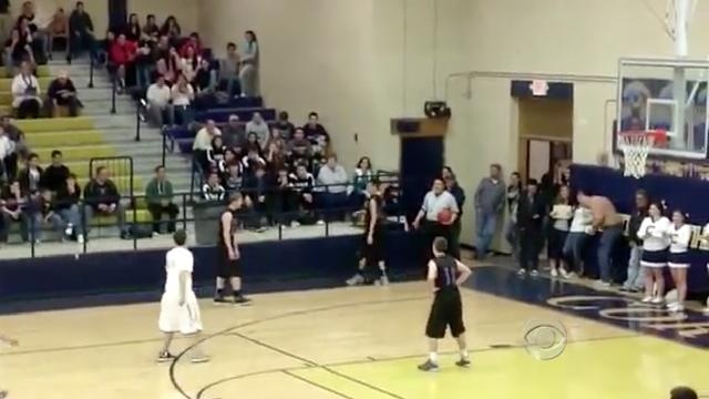 some kids are playing basketball on a court with people watching from the bleachers