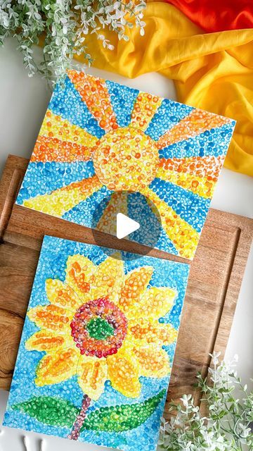 an art project made with colored paper and glue on a wooden board next to flowers