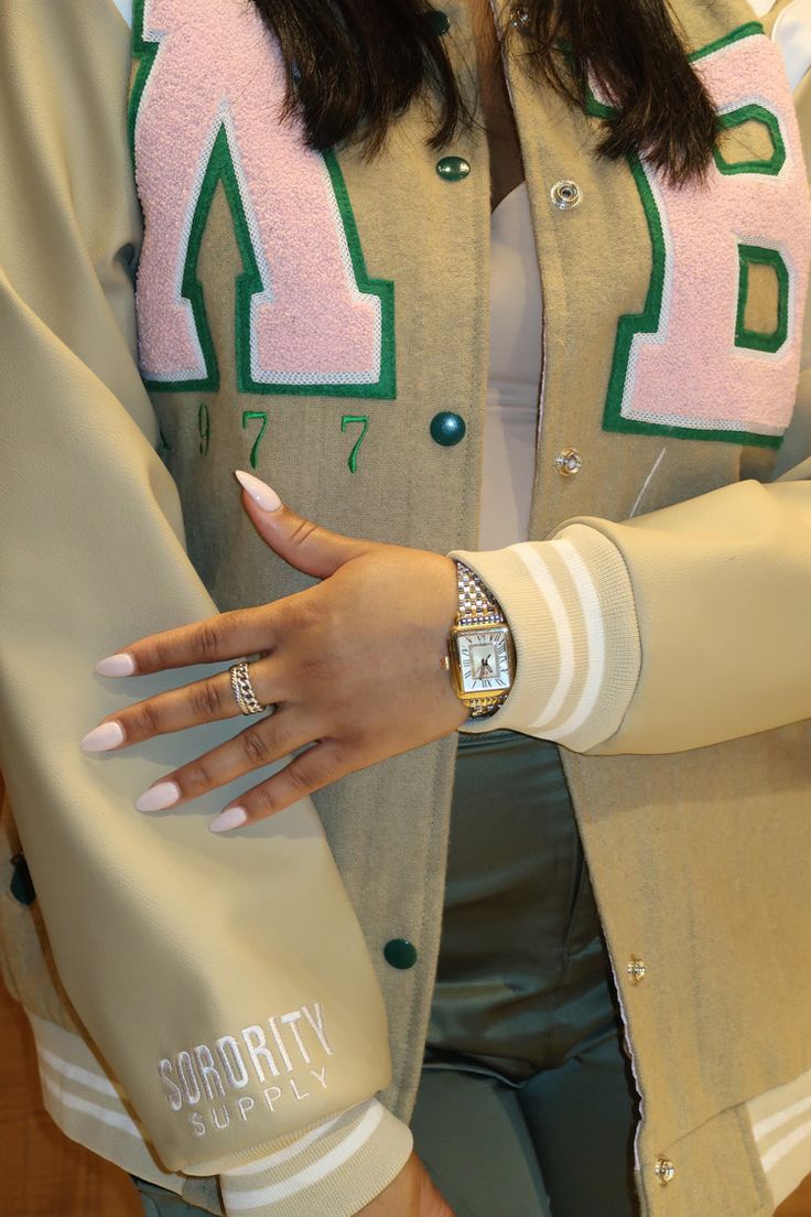 a woman with her hand on the arm of another person wearing a jacket and bracelet