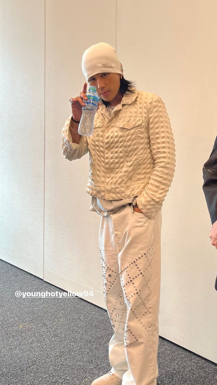 a man in white is holding a water bottle and standing next to another man wearing an all white outfit