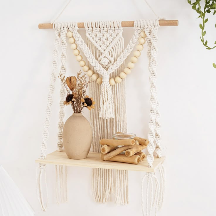 a white macrame hanging from a wall next to a vase with flowers