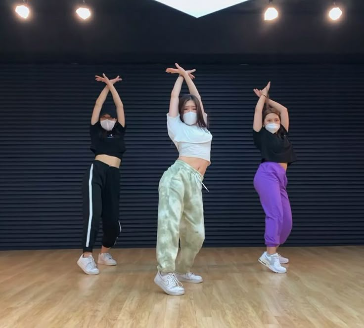 three young women are practicing yoga in an indoor gym area while wearing face masks to protect them from the sun