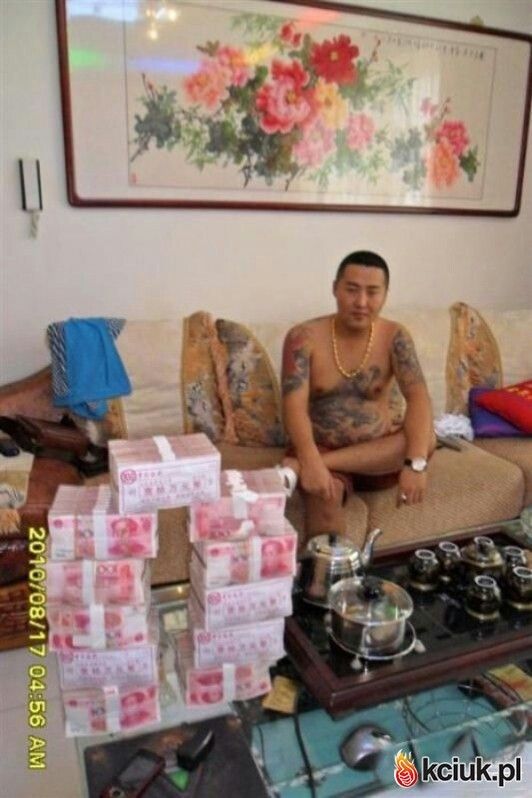 a man sitting on top of a couch next to stacks of money