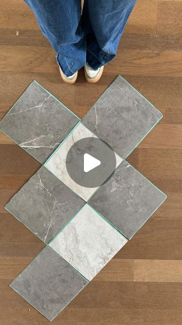 a person standing on top of a wooden floor next to a glass tile area rug