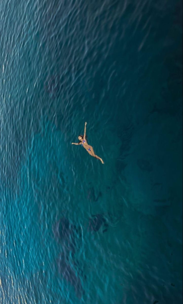 a person floating in the ocean on top of a surfboard