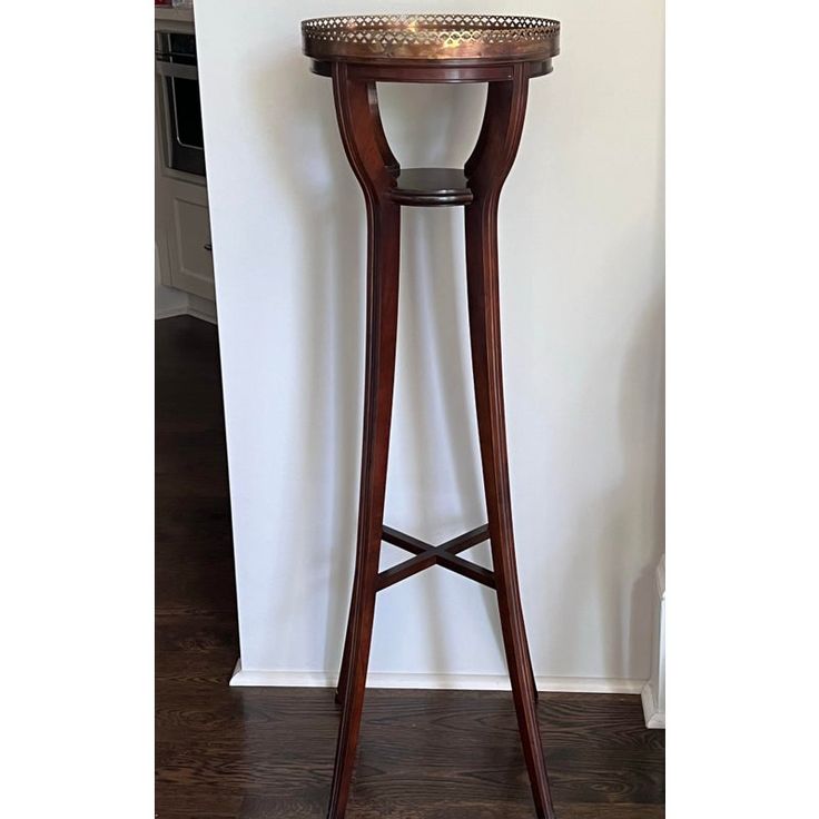 a wooden table with a candle on it and a white wall behind it in the background