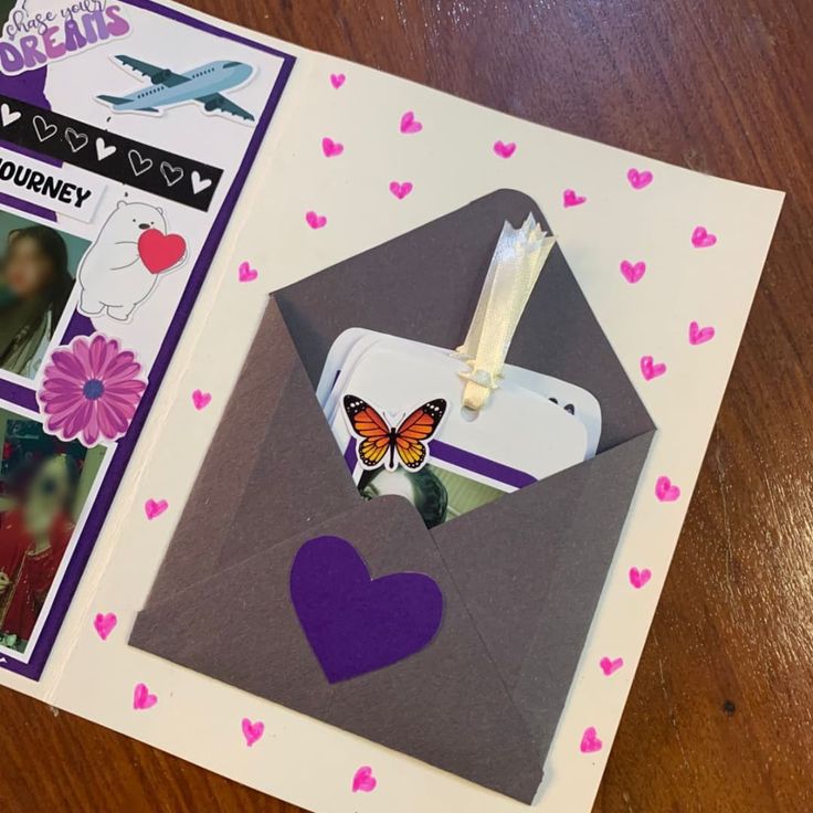 an open envelope with a butterfly on it and some paper hearts attached to the inside