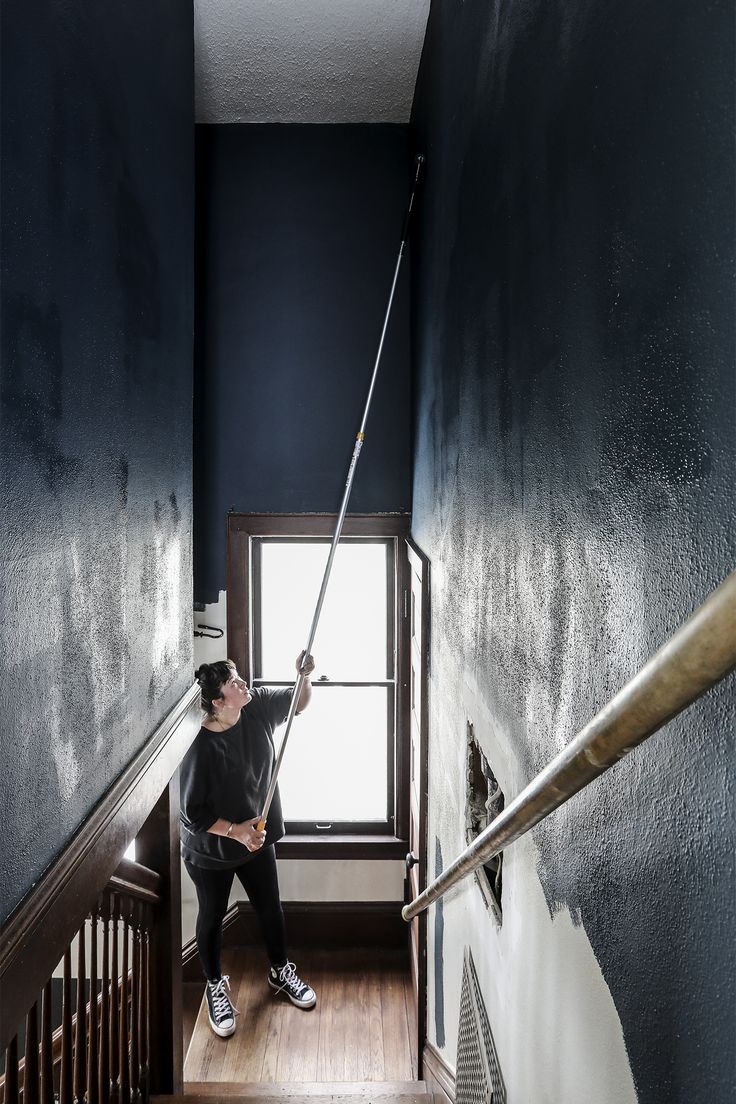 a man is cleaning the stairs with a mop in his hand and looking out the window