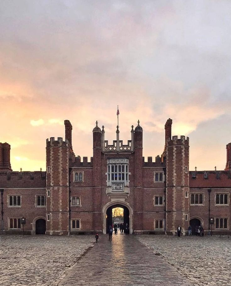 the entrance to an old brick building with people walking in front of it at sunset