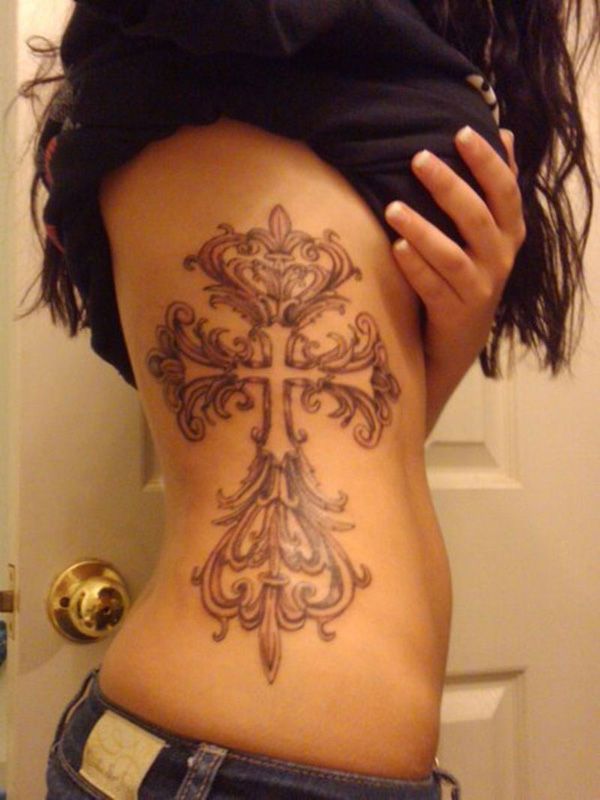 the back of a woman's stomach with tattoos on it and an image of a cross