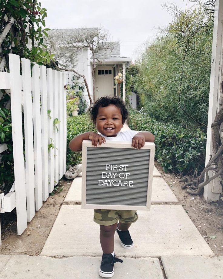 a young child holding up a sign that says first daycare