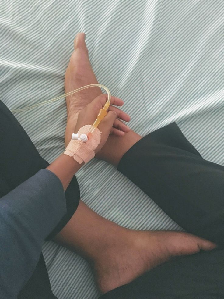 a person laying on a bed with an iv in their hand and bandaged arm