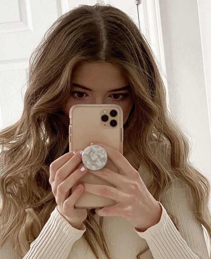 a woman taking a selfie in front of a mirror with her cell phone up to her face