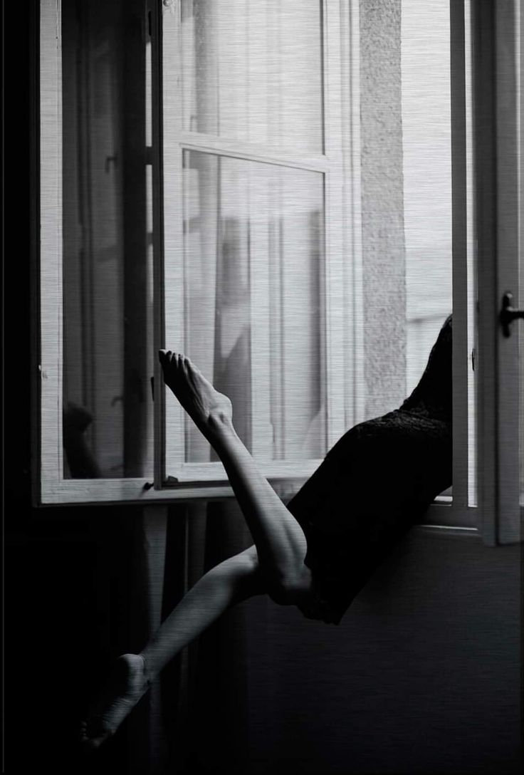 a woman laying on her back in front of a window with the legs hanging out