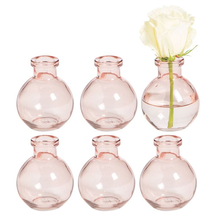 four clear vases with a single white rose in one and six smaller ones on the other