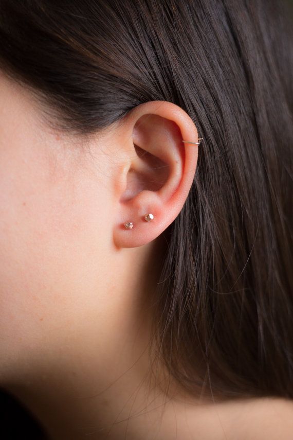 a close up of a person's ear with two small piercings on it