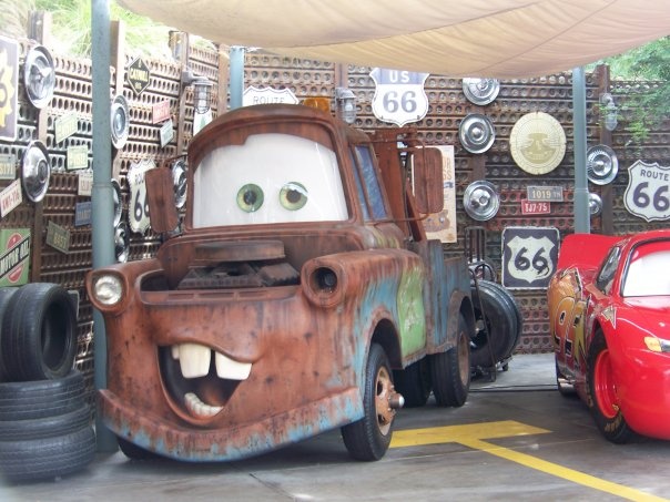 two cars are parked next to each other in front of a wall covered with signs