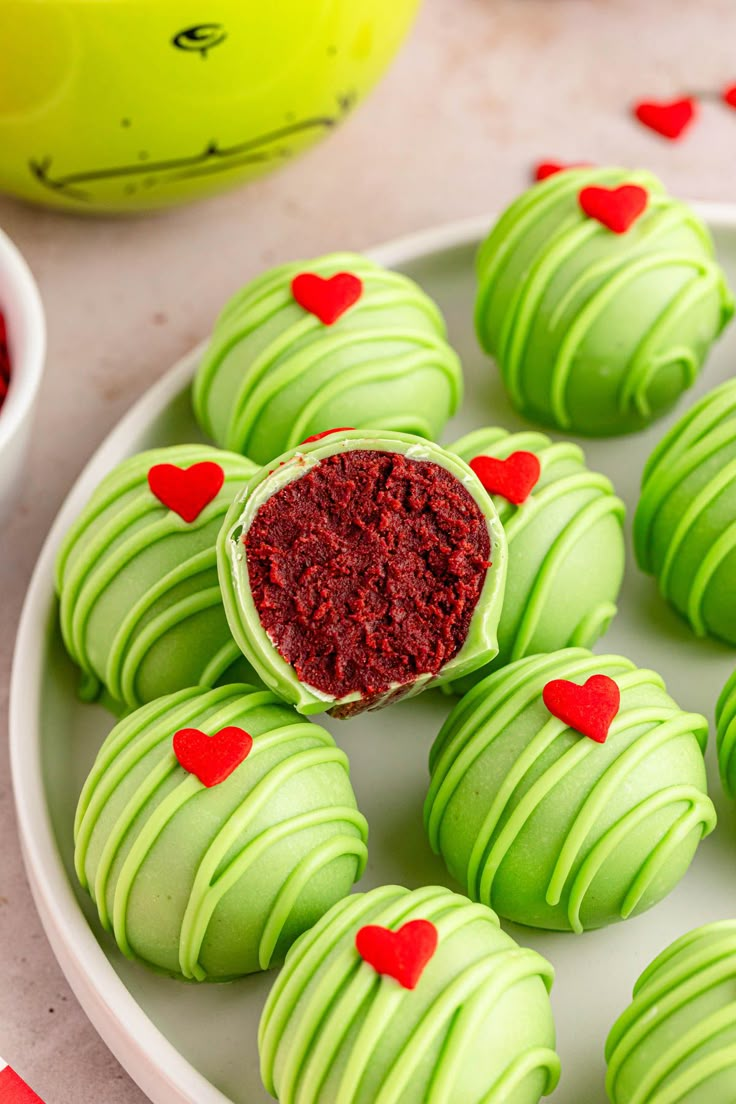 green and red heart shaped desserts on a white plate with candy in the background