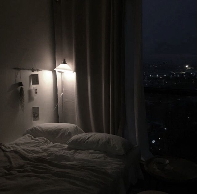 an unmade bed sitting next to a window in a room with white sheets and pillows