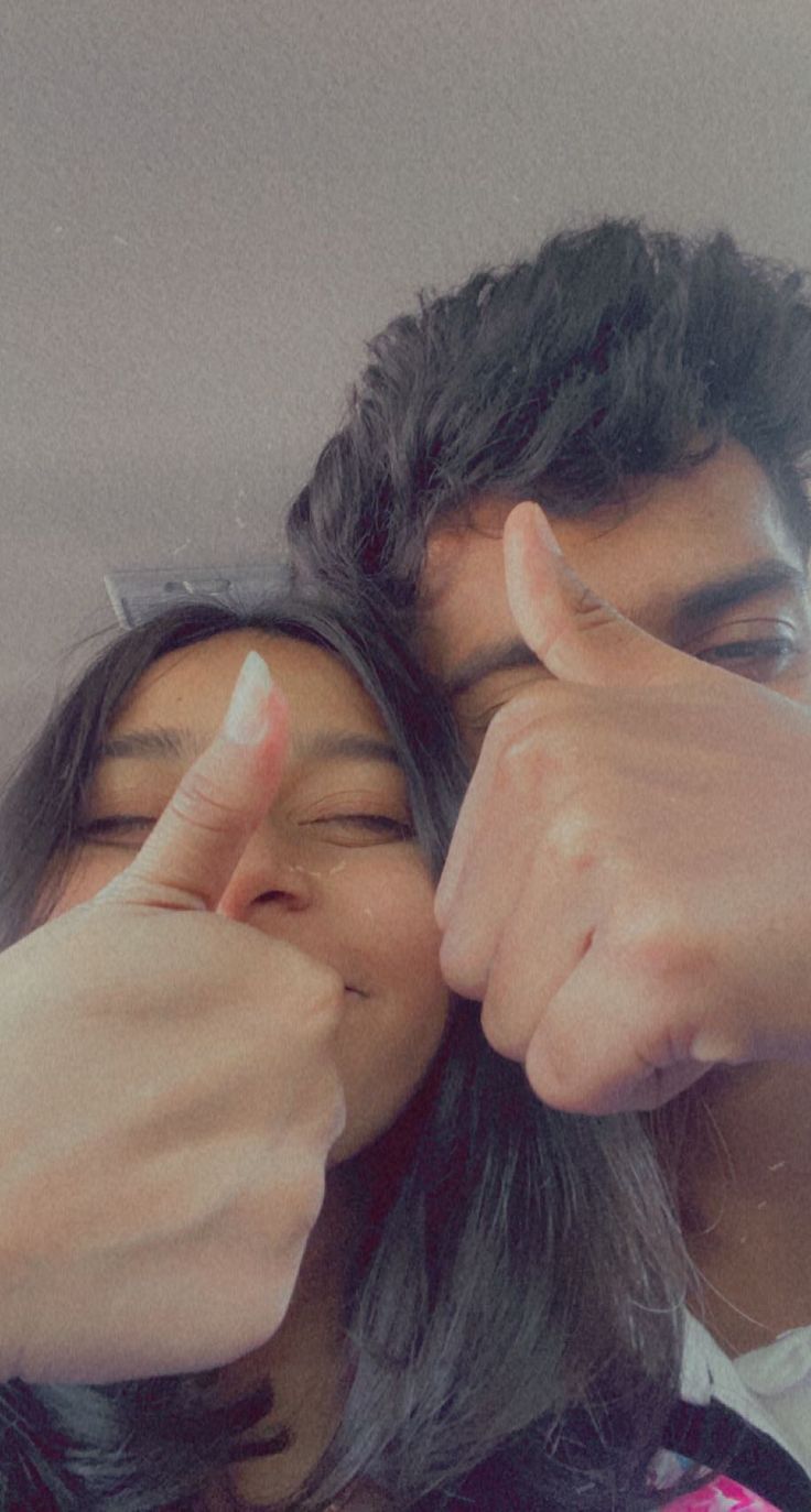 a man and woman giving the thumbs up sign to each other with their fingers in front of them