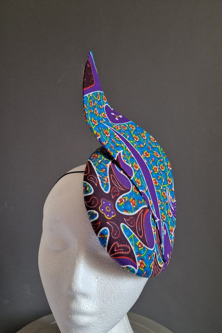 Look a million dollars and exceptionally unique when you turn up at your next event wearing this super cute ankara fabric fascinator to complete your look. It is a button shaped fascinator with a base of sinamay fabric and Wax Cotton Ankara top fabric.  It is secured in place with a black hat elastic. If your hair is brown or blonde I can change the elastic colour to suit (Please specify in your communications). I can make this in other ankara fabric.  As this fascinator is made to order I am un Ascot Hats Fascinators, Fitted Headband Fascinator For Carnival, Adjustable Headpieces For Summer Carnival, Evening Carnival Headband Hat, Carnival Summer Headband Costume Hat, Summer Carnival Costume Headband, Handmade Costume Hat With Structured Crown For Party, Adjustable Headpieces For Carnival, Fitted Headpieces For Carnival And Formal Occasions