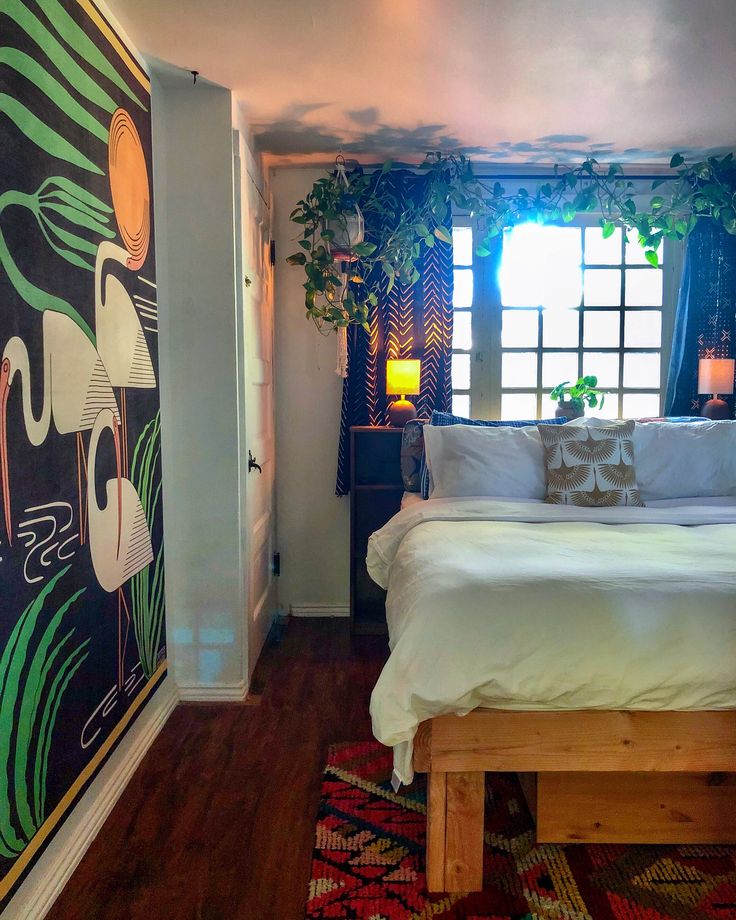 a bed sitting in a bedroom next to a window covered in curtains and potted plants