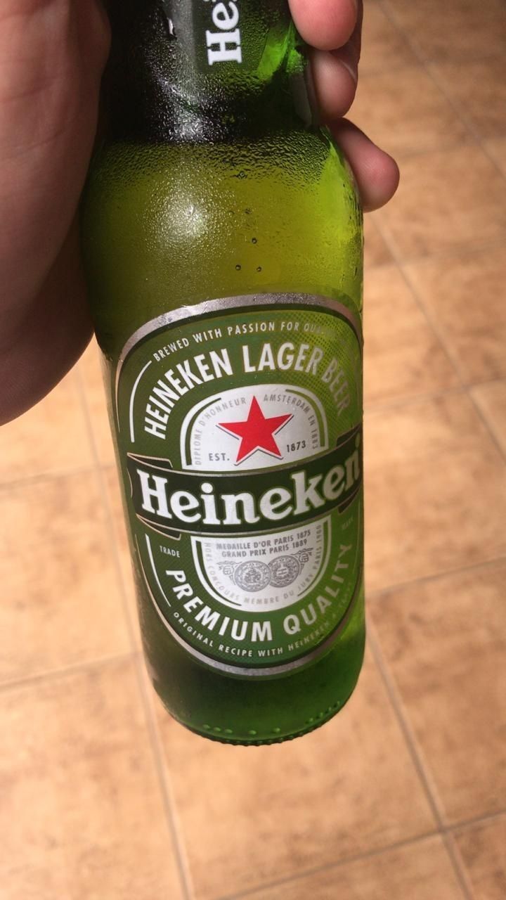 a person holding up a beer bottle in their left hand, with the label heineken on it