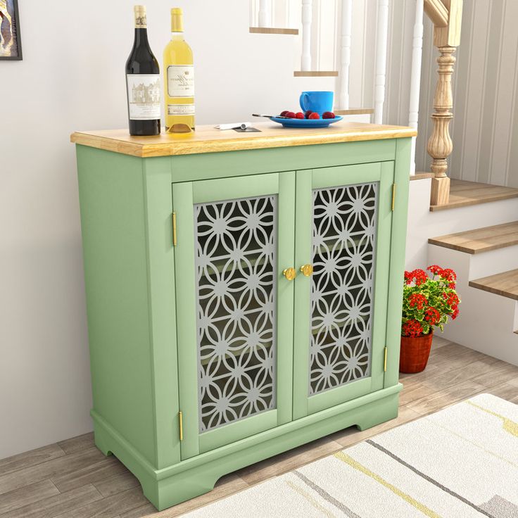 a green cabinet sitting next to a stair case with wine bottles on top of it