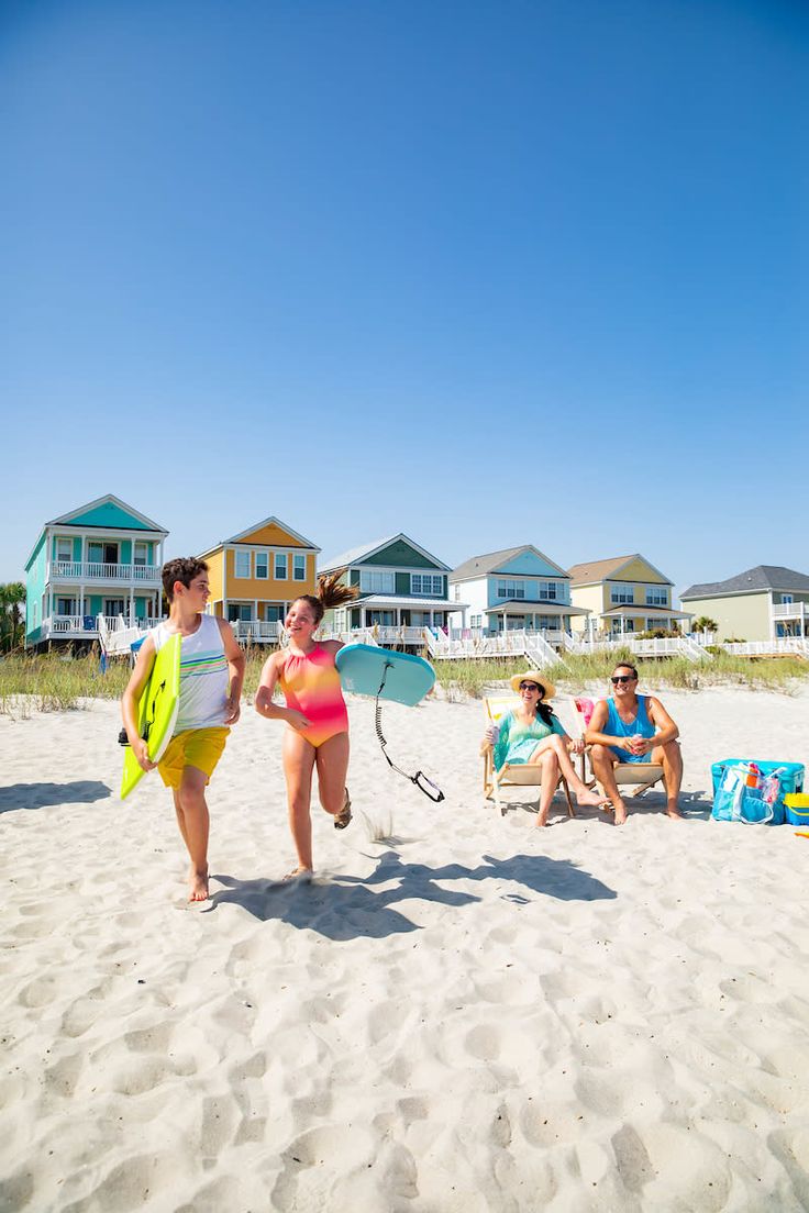 some people are walking on the beach with surfboards and boogie boards in their hands