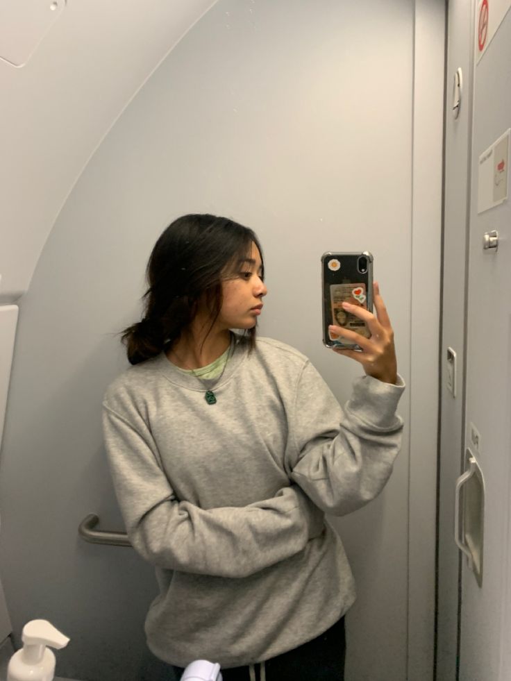 a woman taking a selfie in an airplane bathroom