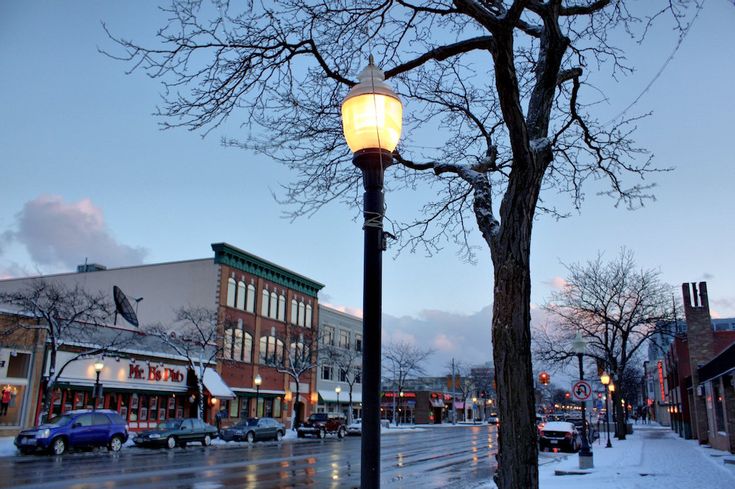 a street light sitting on the side of a road next to a snow covered sidewalk