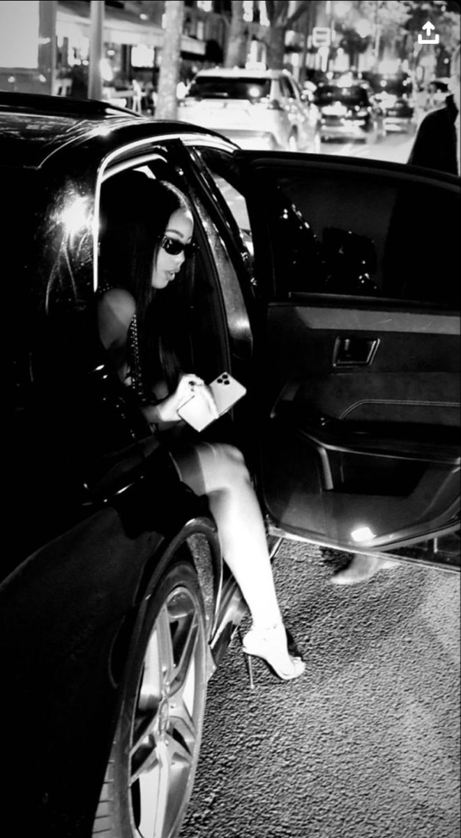 a woman sitting in the back of a car looking at her cell phone