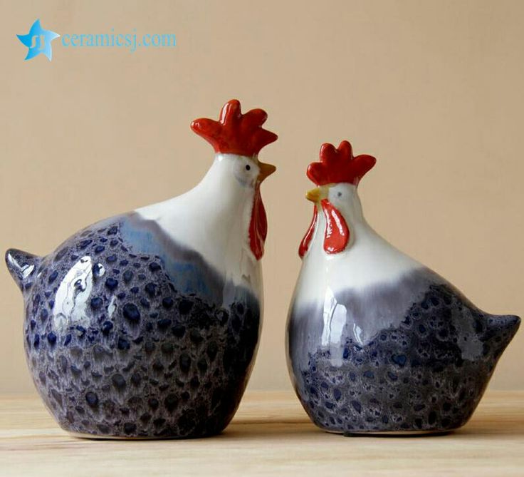 two blue and white ceramic roosters with red beaks sitting side by side on a table