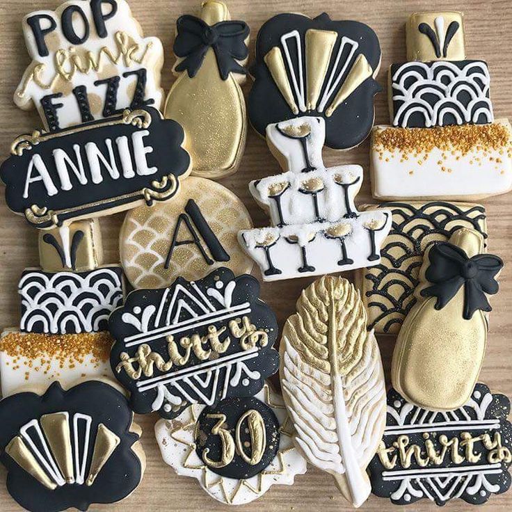 decorated cookies with black and gold accents are arranged on a wooden surface, including one that says pop in the fizz