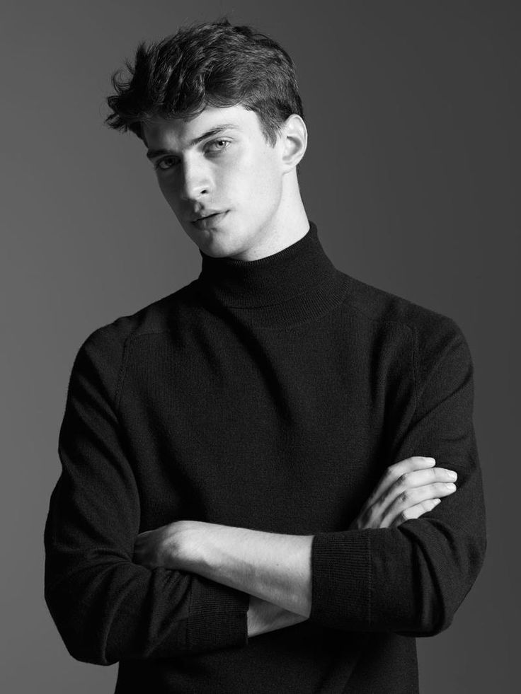 a man in a black turtle neck sweater posing for the camera with his arms crossed