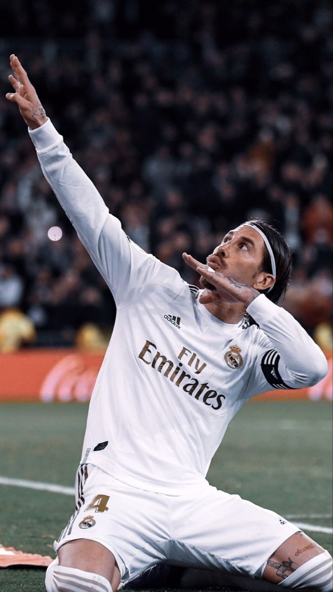 a man sitting on top of a soccer field holding his hand up in the air